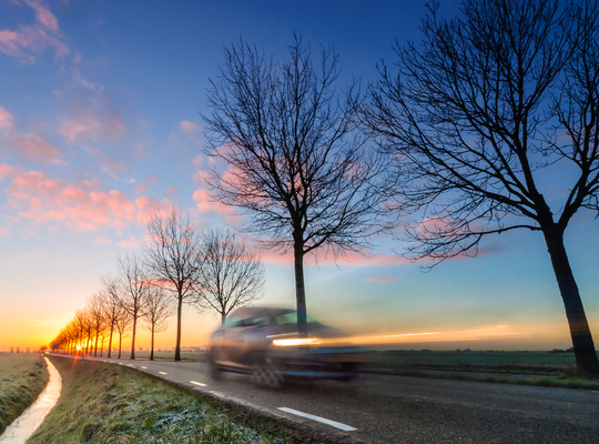 Eenzame auto op de baan bij zonsondergang Eenzame auto op de baan bij zonsondergang